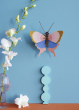 Studio Roof Gold Rim Butterfly decoration picyured on a blue painted wall,orchid flowers in a small pink glass coloured glass vase can be seen to the lest of it 
