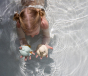 Hevea Upcycled rubber sand duck and sage frog toys being played in the pool by a small child