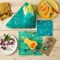 Food laid out on some sheets of the Beeswax Wrap Co seaside pattern wax food covers on a wooden table