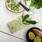 Close up of some green chillies wrapped up in a Beeswax Wrap Company vegan harvest food storage wrap on a white wooden table
