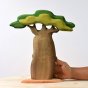 Hand reaching out to hold the Bumbu handmade wooden Baobab tree on a light wooden table
