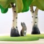 Close up of a Bumbu wooden rabbit figure stood underneath the Bumbu handmade wooden birch tree set on a white background