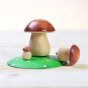 Bumbu eco-friendly hand crafted wooden mushroom toy on a wooden table with one mushroom tipped on its side next to the green base