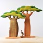 Bumbu sustainable wooden Baobab tree with a thick trunk next to a toy Baobab tree with tall trunk on a light wooden table