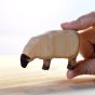Close up of hand holding the Bumbu eco-friendly wooden eating sheep animal toy on a white background