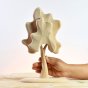 Hand holding the plastic free Bumbu solid wood birch tree on a wooden table in front of a grey background