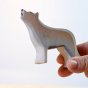 Hand holding the plastic free Bumbu wooden wolf figure in front of a white background