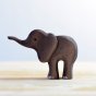 Side view of the Bumbu small handmade wooden elephant figure stood on a light wooden background