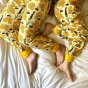 Close up of an adult and childs legs on a white bed wearing the DUNS Sweden organic cotton bee yellow baggy pants