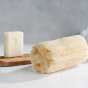 Eco Living eco-friendly exfoliating body loofah scrub on a white wooden table next to a bar of soap and soap holder