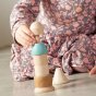 The Grapat Stacking Figure Wooden Stacker Toy, being stacked by a child. Made from natural wood and a pastel blue painted section. Child in background. 