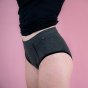 Hey Girls Basic Brief - Grey Period Pants with black trim details worn by a person wearing a black top against a pink background