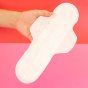 Hey Girls Natural Bamboo & Corn Fibre Disposable Overnight Pad open in someones hand on a pink and red background