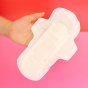 Hey Girls Natural Bamboo & Corn Fibre Disposable Day Pad open in someone's hand on a pink and red background