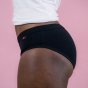 Hey Girls Essential Bikini - black Period Pants worn by a person wearing a white top against a pink background