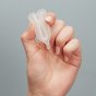 Close up of a hand folding an imse vimse eco-friendly reusable menstrual cup on a grey background