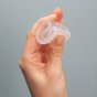 Close up of a hand folding an imse vimse eco-friendly reusable menstrual cup on a grey background