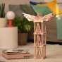 Kapla eco-friendly wooden blocks stacked into a tall tower next to its wooden box on a beige carpet
