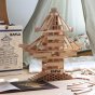 Close up of the Kapla sustainable wooden block set stacked into a tall tower on a wooden floor next to a children's play tent