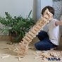 Giant tower of Kapla natural wooden stacking blocks falling over on a wooden floor