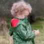 Close up of a boy stood in a green field wearing the Little green radicals recycled plastic rocket rain coat