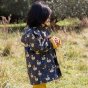 Girl stood sideways wearing the LGR eco-friendly recycled night swimming swan print jacket in a grass field