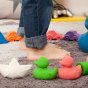 Close up of the oli and carol eco-friendly natural rubber bath toys on a carpet in front of a childs feet
