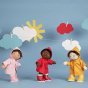 3 olli ella dinkum doll toys stood on a blue background wearing the dress up rainy day outfits in red, yellow and pink