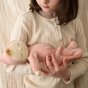 Close up of a girl cradling the Olli Ella soft Dozy Dinkum doll Moppet in front of a cream background