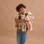 Boy stood smiling and holding a bunch of Olli Ella soft Dozy Dinkum dolls in front of a light brown background