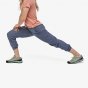 Picture of female model wearing Patagonia Hampi rock pants. Model is lunging to show flexibility and stretch of pants. Picture has a white background. Trouser in picture is navy colour style reference only, this colour is not sold on website.