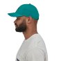 Man stood sideways on a white background wearing the onsize teal green airshed hat
