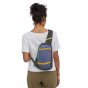 Woman stood backwards wearing the Patagonia eco-friendly smolder blue cross body bag on a white background
