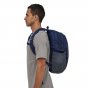 Man stood sideways wearing the Patagonia eco-friendly refugio adults rucksack in the classic navy colour on a white background