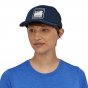 Woman wearing the blue Patagonia eco-friendly resizable alpine logo mesh hat on a white background