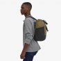 Picture of a male model wearing the Patagonia Arbor classic bag. The picture is taken to show the bag worn from a side angle. The picture has a white background. The bag in the picture is green. This colour bag is not sold on website, picture is used for 