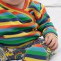 baby wearing long-sleeved wrap-over rainbow striped top and footed baby trousers from piccalilly