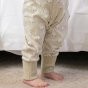 close up of bottom part of toddler wearing cotton tail footless onesie with a white rabbit all-over print on pale cream and stretchy cream cuffs from piccalilly