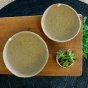 ReSpiin Jute Natural Medium & large woven Bowls from above, on a tan table sheet, a large black table covering and plants next to the bowls