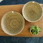 Large and medium Respiin seagrass woven natural bowls on a table on a tan & black placemat and a plant
