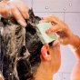 Woman applying the shower blocks 2 in 1 natural shampoo and conditioner bar to her hair in the shower