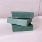 Stack of Shower Blocks eco-friendly lemon and tea tree solid shampoo and conditioner bars on the side of a bath