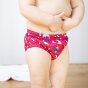 Close up of a toddler stood wearing the Totsbots eco-friendly puffling paddle reusable swim pants on a white background