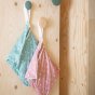 2 Tots bots wet and dry reusable nappy bags hanging on hooks on a wooden wall in the natures rainbow colour
