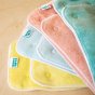 Totsbots natures rainbow bamboo reusable nappy absorbent inserts laid out on a beige background