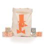 Uncle Goose eco-friendly wooden alphabet blocks on a white background next to the large canvas carry bag