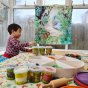 Young boy playing with playdoh in front of the Wonder Cloths organic cotton jungle play fabric
