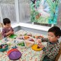 2 boys playing with wooden mandala pieces on a table in front of the Wonder Cloths eco-friendly jungle play cloth