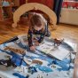 Young girl playing with some wooden toys on the Wonder Cloths eco-friendly Frozen Arctic large play fabric on a wooden floor