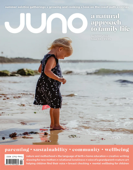 Juno Magazine cover pictures a young child on a beach with their toes in the sand and the water lapping at their feet.